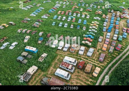 Alte Retro rostig verlassene Autos in grünem Gras, Luft Draufsicht von Drohne über Friedhof von Vintage Autos. Stockfoto