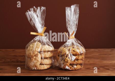 Haferflocken mit Walnüssen und Rosinen und Mandelgebäck in transparenten Tüten auf einem Holztisch. Nahaufnahme Stockfoto