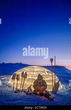 Inuit Mann und Werkzeuge Silhouetten gegen ein brenntes Iglu in der Dämmerung außerhalb Baker Lake, Nunavut. Stockfoto