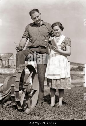 1930ER JAHRE LANDWIRTMANN MANN PAUSIERTE ARBEIT AN MASCHINEN BLICK AUF LESEN EINKAUFEN IN EINEM VERSANDKATALOG MIT FRAU SEINE FRAU - F2421 HAR001 HARS LANDWIRTSCHAFT MÄNNER BESTELLEN LANDWIRTSCHAFT B&W PARTNER SEINE MASCHINEN WAHL BAUERN BERUFE VERBINDUNG ÖL KANN KATALOG-KOOPERATION UNTERSTÜTZEN MID-ADULT MANN MID-ADULT FRAU LÖSUNGEN ZWEISAMKEIT EHEFRAUEN SCHWARZ UND WEISS KAUKASISCHEN ETHNIZITÄT HAR001 ALTMODISCH Stockfoto