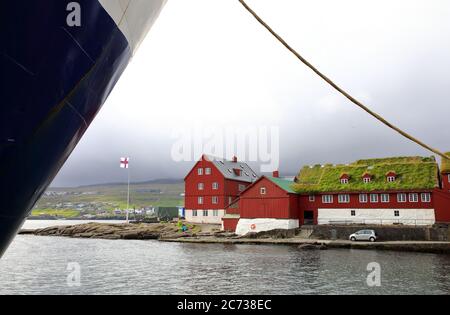 Alte rote Holzgebäude mit Korrugat und Rasendach in der Altstadt (Tinganes) von Torshavn mit einem Schiffsbogen im Vordergrund.Streymoy.Färöer Insel.Territorium von Dänemark Stockfoto