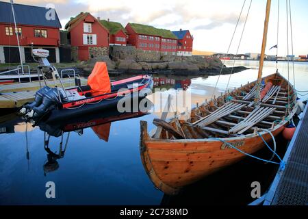 Ein traditionelles Färöer Ruderboot Docking in Torshavn Hafen mit Rasen überdacht Holzhäuser in Tinganes im Hintergrund.Torshavn.Streymoy.Färöer Inseln.Territorium von Dänemark Stockfoto