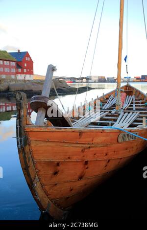 Ein traditionelles Färöer Ruderboot Docking in Torshavn Hafen mit Rasen überdacht Holzhäuser in Tinganes im Hintergrund.Torshavn.Streymoy.Färöer Inseln.Territorium von Dänemark Stockfoto