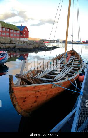 Ein traditionelles Färöer Ruderboot Docking in Torshavn Hafen mit Rasen überdacht Holzhäuser in Tinganes im Hintergrund.Torshavn.Streymoy.Färöer Inseln.Territorium von Dänemark Stockfoto