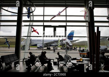 Passagiere warten auf die Abfahrt in Vagar Flughafen mit einem Atlantic Airways Flugzeug auf der Landebahn im Hintergrund.Färöer-Inseln.Dänemark. Stockfoto