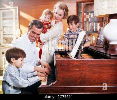 1960S 1970ER JAHRE VATER UND SOHN SPIELEN KLAVIER MIT MUTTER HALTEN TOCHTER UND BRUDER BEOBACHTEN FAMILIE MUSIK IM WOHNZIMMER - KM3532 PHT001 HARS DRINNEN INSTRUMENT BANK MUSIKALISCHE NOSTALGISCHE AUSRÜSTUNG VORSTADTFARBE BEZIEHUNG MÜTTER ALTE ZEIT NOSTALGIE BRUDER ALTE MODE SCHWESTER JUGENDLICH KOMMUNIKATION INSTRUMENTE TASTATUR SÖHNE FAMILIEN FREUDE LIFESTYLE ZUFRIEDENHEIT MUSIKER ELTERNSCHAFT FRAUEN BRÜDER EHEMÄNNER ERWACHSEN GESUNDHEIT HEIM LEBEN KOPIEREN RAUM FREUNDSCHAFT HALBWERTIGEN TÖCHTER PERSONEN ERWACHSEN MÄNNER UNTERHALTUNG GESCHWISTER SCHWESTERN VÄTER MANN UND FRAU MÄNNER UND FRAUEN MUSIKER EHEMÄNNER UND FRAUEN Stockfoto