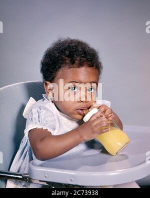 60S BREITÄUGIG AFROAMERIKANISCHE BABY MÄDCHEN BLICK AUF KAMERA SITZEN IN HOCHSTUHL TRINKEN ORANGENSAFT AUS GLASFLASCHE - KN591 HAR001 HARS NIEDLICH GESICHTS SICHERHEIT SNACK FREUDE LIFESTYLE FRAUEN GESUNDHEIT ZU HAUSE LEBEN KOPIEREN RAUM HALBE LÄNGE ORANGE AUSDRÜCKE AUGENKONTAKT GLÜCK WELLNESS ENTDECKUNG AFRO-AMERIKANER AFROAMERIKANISCHE WAHL SCHWARZ ETHNIE STOLZ IN BIS KONZEPTIONELLE STILVOLLE BREITÄUGIGE WACHSTUM JUVENILES BABY MÄDCHEN HAR001 SAFT ALTMODISCHEN AFROAMERIKANER Stockfoto