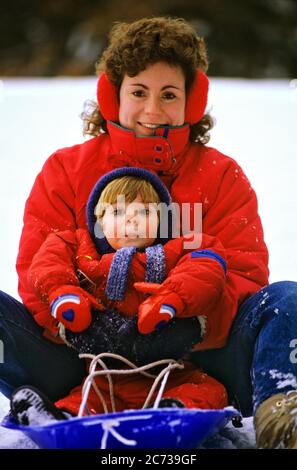 1990S MUTTER UND SOHN IN ROTER KLEIDUNG AUF BLAUEM PLASTIKSCHLITTEN LÄCHELND BLICK AUF KAMERA - KW12006 WAL004 HARS FARBE MÜTTER ALTE ZEIT NOSTALGIE ALTE MODE JUGENDLICH JUNGE ERWACHSENE SÖHNE ERFREUT FAMILIEN FREUDE LIFESTYLE FRAUEN LÄNDLICHES GROWNUP SCHLITTEN GESUNDHEIT HEIM LEBEN KOPIEREN RAUM MENSCHEN KINDER FREUNDSCHAFT HALBLANGE DAMEN PERSONEN MÄNNER VERTRAUEN ALLEINERZIEHEND WINTERZEIT AUGENKONTAKT ALLEINERZIEHEND GLÜCK FRÖHLICH ABENTEUER FREIZEIT UND AUFREGUNG NIEDERWINKLIG ERHOLUNG LÄCHELT VERBINDUNG FRÖHLICH BABY JUNGE WINTERLICH ZUSAMMENARBEIT WACHSTUM JUVENILES MÜTTER ZWEISAMKEIT JUNGE ERWACHSENE FRAU KAUKASISCHE ETHNIE Stockfoto