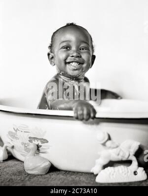 1940ER JAHRE LÄCHELNDES AFROAMERIKANISCHES BABY BEDECKT MIT SEIFENSAUGEN SITZEN IN EINEM BADEWANNE WASCHBECKEN BLICK AUF KAMERA - N234 HAR001 HARS SÄUGLING FREUDE LIFESTYLE BADEWANNE GESUNDHEIT HEIM LEBEN KOPIEREN RAUM HALBE LÄNGE MÄNNER SPIRITUALITÄT VERTRAUEN AUSDRÜCKE B & W AUGENKONTAKT BEDECKT HUMORVOLLES GLÜCK WELLNESS KOPF UND SCHULTERN FRÖHLICHE STÄRKE AFRO-AMERIKANER AFRO-AMERIKANER AUFREGUNG SCHWARZ ETHNICITY KOMISCHEN STOLZ EIN IN LÄCHELT KONZEPTUELLE BECKEN KOMÖDIE FRÖHLICH STYLISH BABY JUNGE WACHSTUM JUVENILES SEIFSUDS SCHWARZ UND WEISS HAR001 ALTMODISCHE AFROAMERIKANER Stockfoto