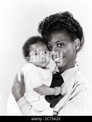 1940ER JAHRE 1940ER JAHRE LÄCHELND AFROAMERIKANISCH FRAU MUTTER BLICK AUF KAMERA HALTEN SÄUGLING BABY MÄDCHEN TOCHTER UMARMEND WANGE ZU WANGE - N574 HAR001 HARS UMARMEND ALTE MODE 1 JUGENDLICH GESICHTS JUNGE ERWACHSENE BALANCE TEAMWORK SÄUGLING STARK ERFREUT FREUDE LIFESTYLE ZUFRIEDENHEIT FEIER FRAUEN GESUNDHEIT HEIM LEBEN KOPIEREN RAUM HALBE LÄNGE DAMEN TÖCHTER PERSONEN INSPIRATION FÜRSORGE VERTRAUEN AUSDRÜCKE B&W AUGENKONTAKT TRÄUME GLÜCK WELLNESS KOPF UND SCHULTERN FRÖHLICHE STÄRKE AFROAMERIKANER AFROAMERIKANER HOFFNUNG AUFREGUNG MÄCHTIGE SCHWARZE ETHNIZITÄT STOLZ GELEGENHEIT LÄCHELT VERBINDUNG KONZEPTIONELL Stockfoto