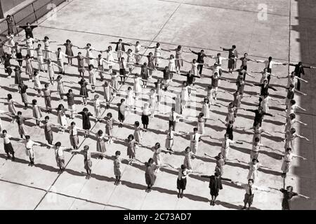 1920ER JAHRE LEHRER BEAUFSICHTIGTE BILDUNG VON ÖFFENTLICHEN SCHULE JUNGEN UND MÄDCHEN TRAINING IN BILDUNG AUF BETON SPIELPLATZ - S6272 HAR001 HARS GLEICHGEWICHT ÖFFENTLICHE TEAMARBEIT BEWEGUNG STRETCHING LIFESTYLE OVERHEAD FRAUEN GESUNDHEIT KOPIEREN RAUM VOLLE LÄNGE KÖRPERLICHE FITNESS INSPIRATION MÄNNER GNADE VERTRAUEN S & W SCHULEN WEITWINKEL AKTIVITÄT GRAD KÖRPERLICHE WELLNESS HOCHWINKEL KRAFT UND ERHOLUNG RICHTUNG ÜBUNGEN IN DER LEISTUNG AUTORITÄT BILDUNG BERUFE PRIMÄRE KONZEPTIONELLE CALISTHENICS FLEXIBILITÄT GYMNASTIK MUSKELN GRAD SCHULWACHSTUM JUGENDLICHE MITTLEREN ERWACHSENEN MITTLEREN ERWACHSENEN FRAU PRE-TEEN Stockfoto