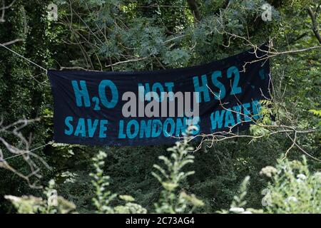 Denham, Großbritannien. Juli 2020. 13 Ein Banner mit der Aufschrift ‘H20 Not HS2’ hängt in der Nähe des Denham Protection Camp am Fluss Colne. Umweltaktivisten von HS2 Rebellion versuchen, den Bau der 106 Mrd. £schweren Hochgeschwindigkeits-Eisenbahnverbindung HS2 zu verhindern oder zu verhindern, die während ihrer geplanten 120-jährigen Lebensdauer einen Nettobeitrag zu den CO2-Emissionen leisten wird. Kredit: Mark Kerrison/Alamy Live Nachrichten Stockfoto