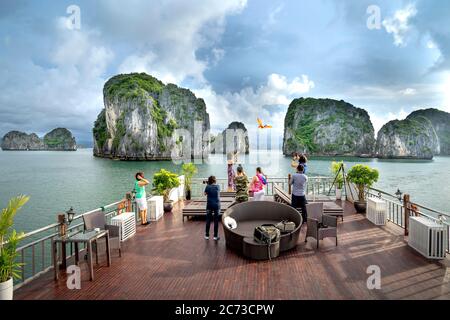 Ha Long Bay, Quang Ninh Provinz, Vietnam - 3. Juli 2020: Touristen vom offenen Deck des Schiffes bewundern die herrliche Landschaft der Halong Bay. Stockfoto