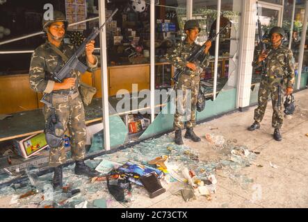 CARACAS, VENEZUELA, MARCH1989 - Soldaten der venezolanischen Armee bewachen den geplünderten Laden während des Ausnahmezustands in Caracas, bekannt als Caracazo. Stockfoto