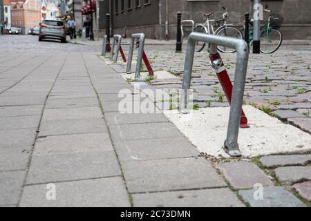 Parksperre am Parkplatz entlang der Straße in der Stadt, Autos und Fahrräder geparkt. Pflaster mit Gras bewachsen. Stockfoto