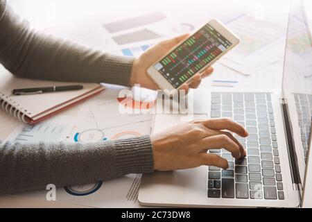 Geschäftsfrau analysieren Geschäftsbericht Diagramm und Finanzdiagramm mit Smartphone und Computer Laptop in der Unternehmenszentrale. Stockfoto