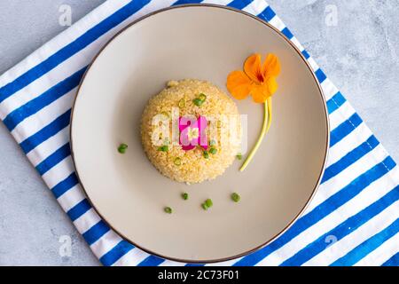 Quinoa-Teller-Präsentation mit essbaren Blumen dekoriert Stockfoto