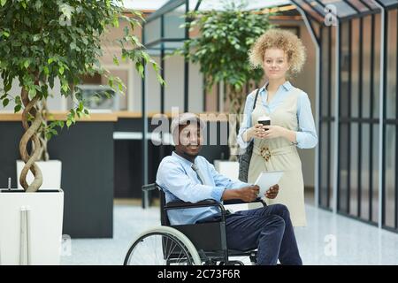 Porträt eines multiethnischen Paares, das in der Mall stehend in der Nähe eines behinderten afrikanischen Mannes auf die Kamera schaut Stockfoto