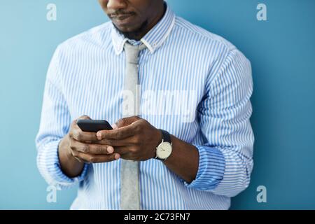 Nahaufnahme eines jungen afrikanischen Mannes, der eine Nachricht auf seinem Handy eintippt Stockfoto