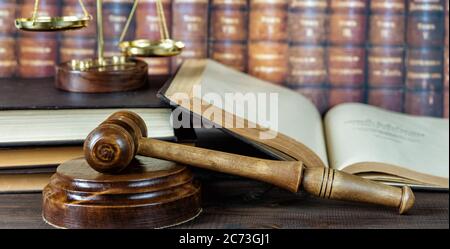 Holz Hammer, soundblock, Waagen und Öffnen altes Buch vor dem Hintergrund einer Reihe antiker Bücher in Leder gebunden Stockfoto