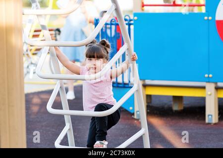 Kinder spielen auf dem Spielplatz im Freien. Gesunde Sommeraktivitäten für Kinder. Kleines Mädchen klettern im Freien. Lifestyle-Porträt Stockfoto