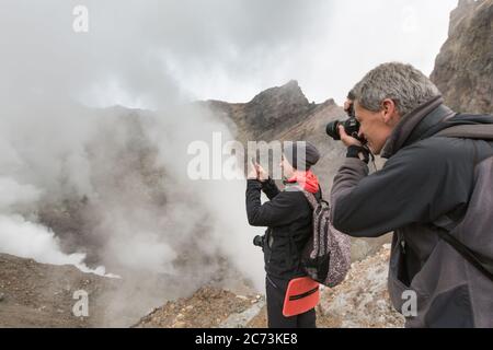 Touristen macht Bilder von dramatischen vulkanischen Landschaft, aggressive heiße Quellen, Eruption Fumarole, Gas-Dampf-Aktivität in Krater aktiven Vulkan Stockfoto