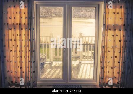 Blick auf das Morgenlicht, das durch die fenstertüren zu einer Terrasse führt. Stockfoto