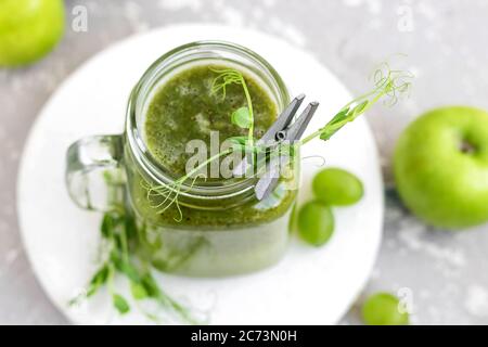 Grüner Vitamin-Smoothie mit Trieben von jungen Erbsen. Grüner Smoothie aus Apfel, Trauben und Kiwi Stockfoto