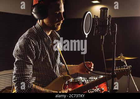 Junge kaukasische Profi-Gitarrist singen am Mikrofon und Gitarre gleichzeitig spielen. Musik, Rock and Roll Konzept Stockfoto