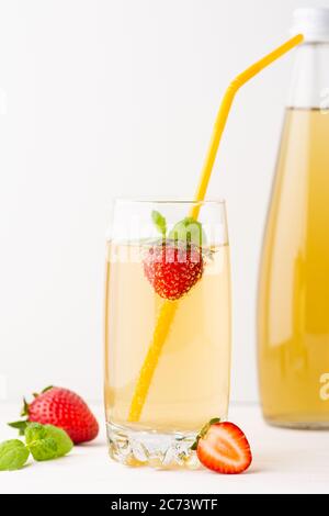 Grüner Soda-Tee mit Erdbeeren und Minze wird in eine Glasschale gegossen. Stockfoto