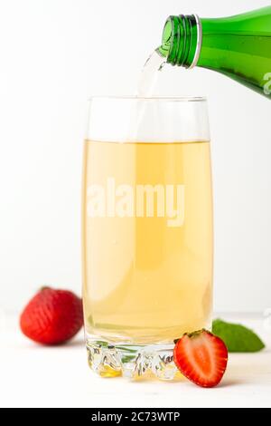 Grüner Soda-Tee mit Erdbeeren und Minze wird in eine Glasschale gegossen. Kohlensäurehal Funkelnd. Stockfoto