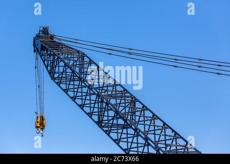 Große Takelage Kran Closeup Arm verlängerte Sektion mit Stahlseilen und zwei gelben Haken Industriebau mechanische Ausrüstung in blauen Himmel. Stockfoto