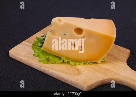 Maasdamer Käse auf dem Bord serviert Salatblättern und Rosmarin Stockfoto