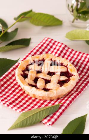 Offener Kuchen aus Mürbeteig mit Kirschen und Himbeeren, ein Kuchen mit Serviette auf weißem Hintergrund Stockfoto