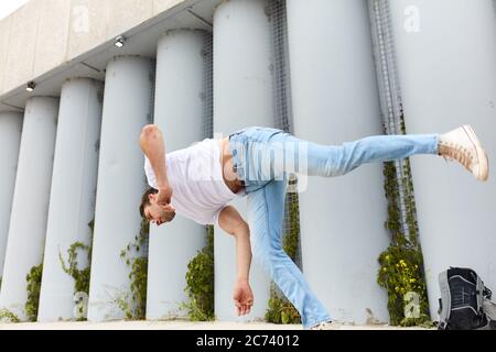 Junger motivierter Mann dreht seinen Körper in der Luft. Tänzer auf der Straße. Hip Hop, Kunstkonzept Stockfoto