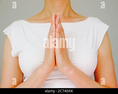 Eine Frau mit natürlichen Nägeln macht den Namaste Gruß Stockfoto