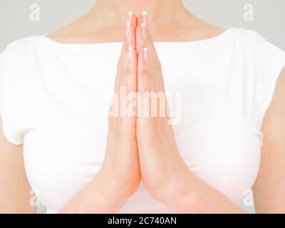 Eine Frau mit natürlichen Nägeln macht den Namaste Gruß Stockfoto