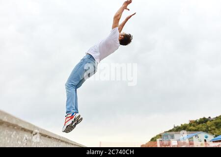 Junger Mann tut zurück Flip in der Straße. Sport Aktivitäten im Freien.Foto in voller Länge. Platz kopieren Stockfoto