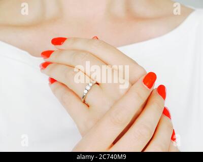Weibliche Hände mit rot gepflegten Nägeln zeigen einen diamantenen Verlobungsring Stockfoto
