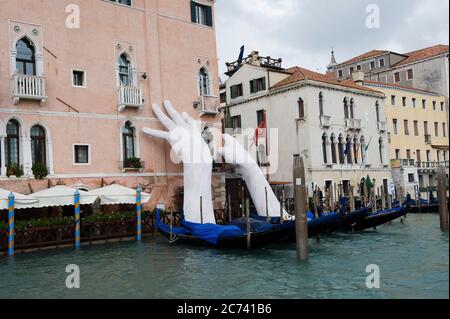 Europa, Italien, Venetien, Venedig. Stadt an der Adria-Lagune gebaut. Stadt der Wasserkanäle statt Straßen. Hauptstadt der Serenissima Republik Venedig. UNESCO-Weltkulturerbe. Die Unterstützungsarbeit von Lorenzo Quinn am Canale Grande von Venedig unterstützt das Ca'Sagredo Hotel. Stockfoto