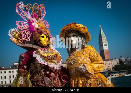 VENEDIG, ITALIEN - 28. FEBRUAR 2020: Zwei Masken posieren während des Karnevals von Venedig vor dem San Marco Becken Stockfoto