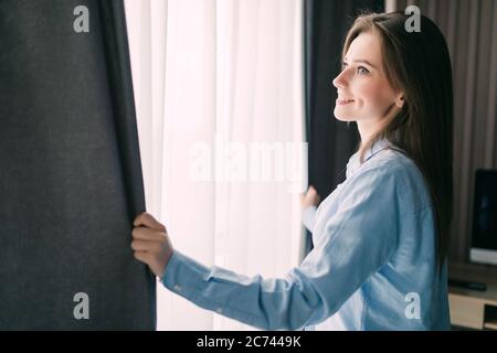 Junges Mädchen öffnet die Vorhänge und Entspannung am Morgen Stockfoto