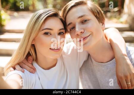 Schöne junge Paar macht Selfie zusammen. Cool junge und hübsches Mädchen mit blonden Haaren glücklich Blick in der Kamera, während die Fotos auf dem Handy Stockfoto