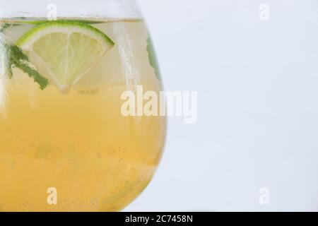 Nahaufnahme eines Kristallglases, gefüllt mit Mojito mit Soda, Eis und Kalk Keilen und Minzblättern auf weißem Hintergrund. Cocktailkonzept. Stockfoto