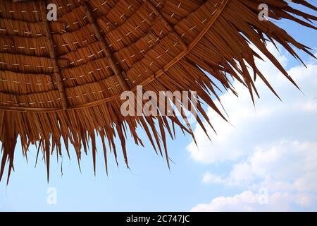 Strohschirm am Strand gegen blauen sonnigen Himmel Stockfoto