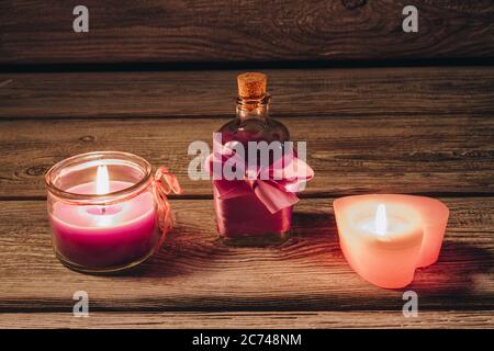 Spa Ölflasche mit Fliege und brennenden Kerzen auf Holz. Stockfoto