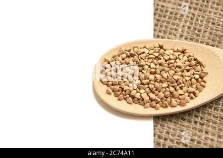 Buchweizenkörner. Gesunde Ernährung. Weißer Hintergrund. Holzlöffel Stockfoto