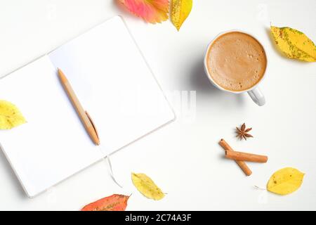 Herbst flach Lay Zusammensetzung. Tasse Kaffee, geöffnetes Papierheft mit Stift, Zimtstangen, gefallene Blätter auf weißem Holzschreibtisch. Herbst, Herbst Konzept. Stockfoto