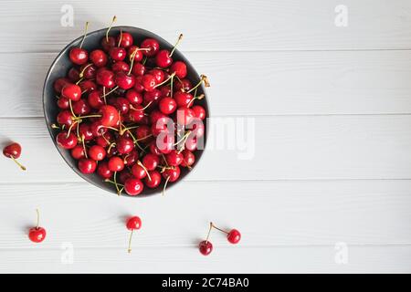 Reife Kirschen in Schale auf dem weißen Holztisch, direkt darüber Stockfoto