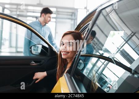 Junges Paar im Autohaus wählt ein Auto Stockfoto